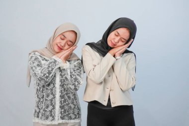 Açık mavi arka planda başörtüsü takan iki kız kardeşin ifadesi.