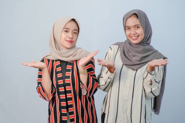 İki Asyalı Endonezyalı tesettürlü kadının, kahverengi ve beyaz çizgili giysiler içindeki mutlu ifadeleri.