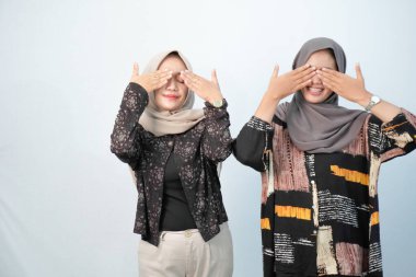 Siyah ve kahverengi desenli giyinen iki Endonezyalı kadın mavi-beyaz arka planda diğer renklerle birleştirilmiş.