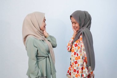 İki Endonezyalı kadın başörtüsü takıyor yeşil ve beyaz desenli çiçek desenli kıyafetler giyiyorlar.