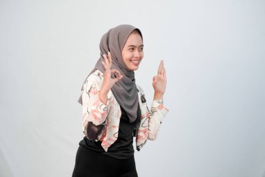 Endonezyalı kadın tesettür giyiyor beyaz elbiseler giyiyor ve renk kombinasyonu yapıyor.