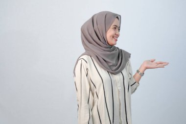 Endonezyalı Asyalı kadının bedeni tesettüre bürünmüş beyaz elbiseler ve çizgili motifler giyiyor.