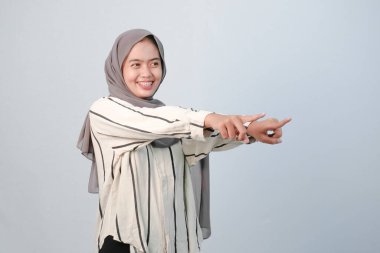 Endonezyalı Asyalı kadının bedeni tesettüre bürünmüş beyaz elbiseler ve çizgili motifler giyiyor.