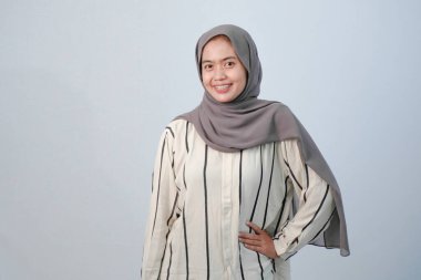 Endonezyalı Asyalı kadının bedeni tesettüre bürünmüş beyaz elbiseler ve çizgili motifler giyiyor.