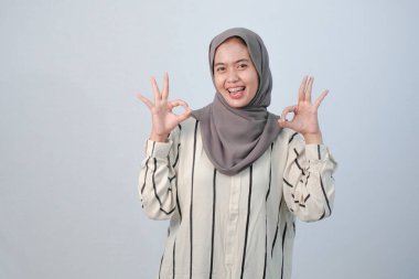 Endonezyalı Asyalı kadının bedeni tesettüre bürünmüş beyaz elbiseler ve çizgili motifler giyiyor.