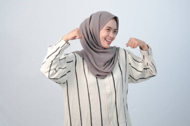 Endonezyalı Asyalı kadının bedeni tesettüre bürünmüş beyaz elbiseler ve çizgili motifler giyiyor.