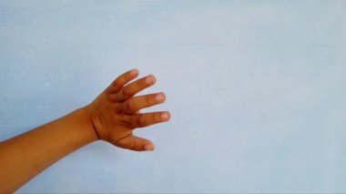 Mavi arka planda el sallayan bir bebek