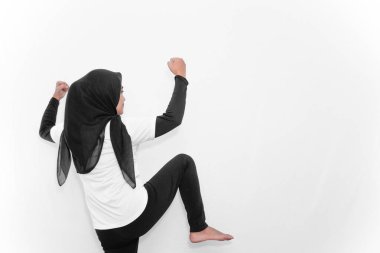 Beyaz tesettürlü, jimnastik yapan, yumruklarını sıkan bir kadın..