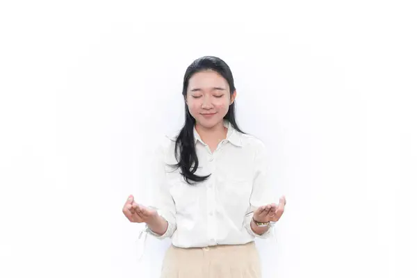 Beyaz elbiseli Asyalı kadın gülümsüyor ve meditasyon yapıyor ya da zihnini yatıştırıyor.