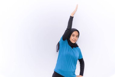 Türbanlı ve mavi elbiseli kadınlar için ısınma egzersizi. Bir elini kaldırıyor.