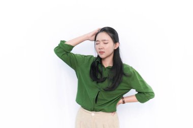 Yeşil elbiseli Endonezyalı bir Asyalı kadının ifadesi ya karışık ya da baş ağrısı var.