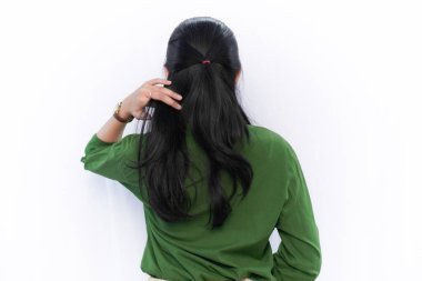 Saçını tutan yeşil elbiseli Endonezyalı Asyalı kadının ifadesi