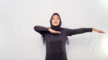 Siyah tesettürlü bir kadın tarafından yapılan ısınma hareketleri.