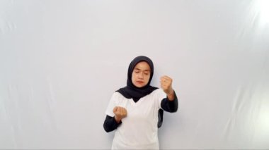 Başörtüsü ve beyaz elbiseler giyen kadınların yaptığı ısınma hareketleri.