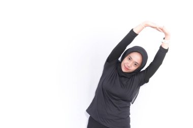 Siyahlı tesettür giyen Endonezyalı kadın ısınıyor.