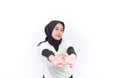 Endonezyalı kadın tesettür giyiyor beyaz kıyafetler giyiyor ısınma egzersizleri yapıyor.