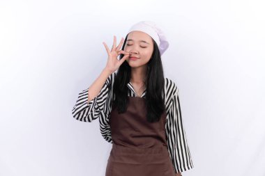 Aşçı üniformalı Endonezyalı kadın gülümsüyor ve yemeğinin lezzetini gösteriyor.