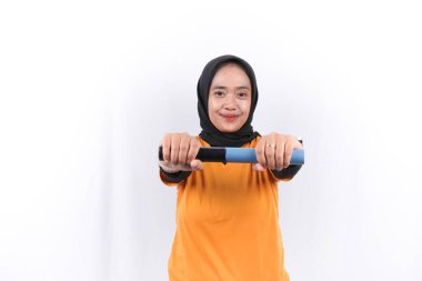 Endonezyalı kadın spor yaparken sarı başörtüsü takıyor.