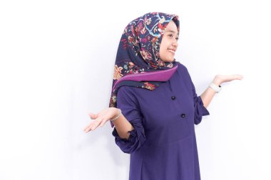 Mavi Müslüman kıyafeti giyen Endonezyalı kadın gülümsüyor ve iki elini de açıyor.