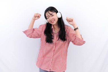 Kırmızı çizgili elbise giyen Asyalı kadın gülümsüyor ve müzik dinliyor.