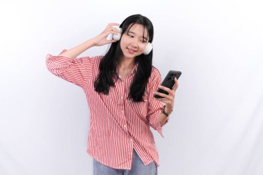 Kırmızı çizgili elbise giyen Asyalı kadın gülümsüyor ve müzik dinliyor.