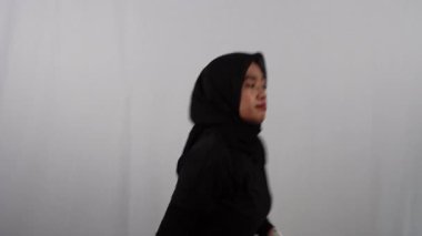Endonezyalı kadın tesettürlü ve siyah elbiseli kadın kapalı alanda egzersiz yapıyor.