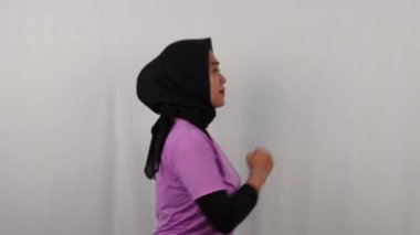 Endonezyalı kadının mor tesettüre bürünmüş iç mekan egzersizi yaparken videosu.