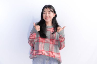 Kırmızı kareli süveter giyen Endonezyalı kadın başparmağını kaldırıyor.