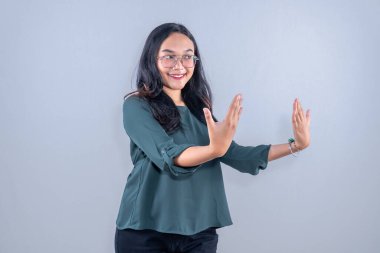 Yeşil gözlüklü, gülümseyen ve parmaklarını gösteren Asyalı Endonezyalı kadın.