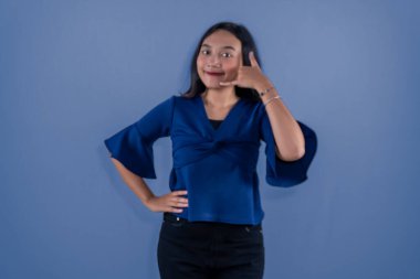 Asyalı Endonezyalı uzun kollu mavi gömlek giyen kadın telefon numarası yapıyor.