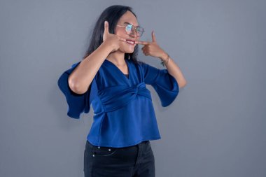 Asyalı Endonezyalı uzun kollu mavi gömlek giyen, gülümseyen ve dişlerini gösteren bir kadın.