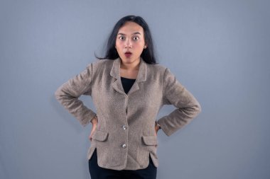 Kahverengi takım elbiseli Endonezyalı bir kadın şaşkınlık içinde bakıyor..