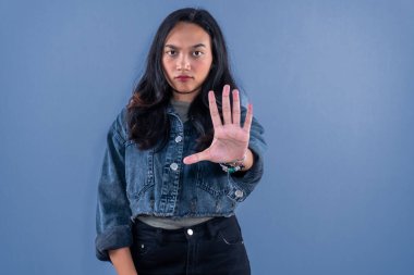 Mavi kot ceket giyen Asyalı kadın dur işareti veriyor.