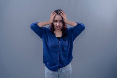 Endonezyalı mavi elbiseli kadın baş ağrısı ya da baş dönmesi yaşıyor