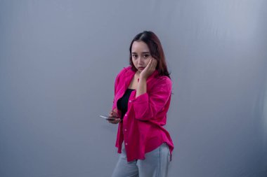 Kırmızı elbiseli Asyalı kadın. Yanak ve akıllı telefon tutuyormuş.