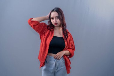 Turuncu elbiseli Endonezyalı bir kadın kendini iyi hissetmiyor, başını tutuyor..