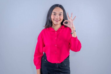 Endonezyalı kırmızı elbise giyen, gülümseyen ve işaret veren Asyalı kadın.