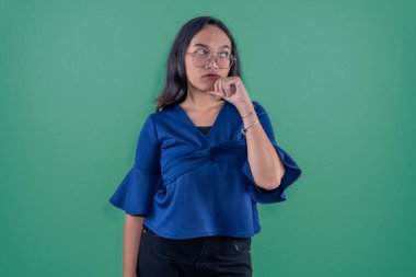 Asyalı Endonezyalı kadın mavi kıyafetler giyiyor. Düşünüyor ya da ilham arıyor.