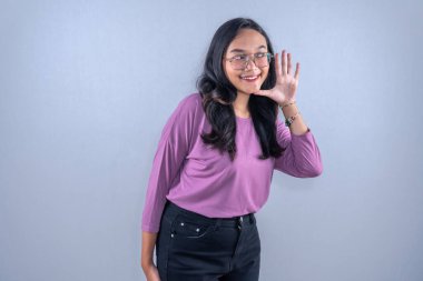 Mor kıyafetler giyen Endonezyalı kadın gülümsüyor ve bir şeyler vermek istiyor.