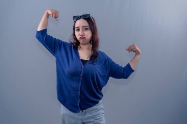 Asyalı Endonezyalı kadın mavi elbiseler giyerek başarıyı kutlamak için ellerini kaldırıyor.