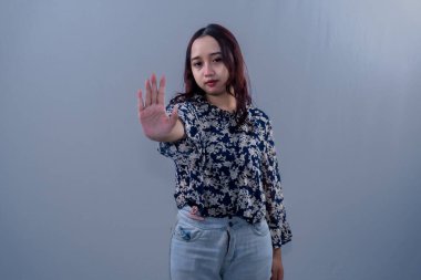 Siyah çiçekli gömlek giyen Endonezyalı kadın dur işareti veriyor.