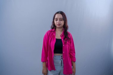 Asyalı Endonezyalı kırmızı elbiseli kadın ayakta durup bir şey düşünüyor.