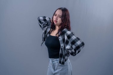 Siyah kareli gömlek giyen Endonezyalı bir kadının tüm vücudu ağrıyor.