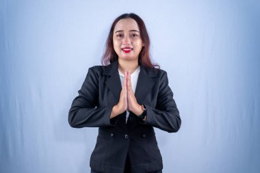 Elleri göğsünün önünde olan gülümseyen bir kadın şükranlarını sunar ya da saygılı bir şekilde selamlar..