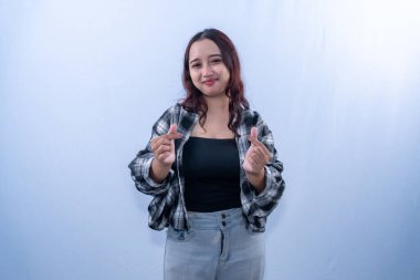 Endonezyalı, kareli gömlek giyen, gülümseyen ve parmaklarıyla aşk işareti yapan Asyalı kadın.