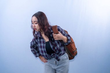 Ekose gömlek giyen Asyalı kadın sırt çantası taşıyor.