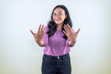 Mor giyinmiş, gülümseyen ve parmaklarını gösteren Endonezyalı Asyalı kadın.