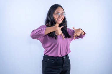 Mor gömlekli ve gözlüklü genç bir Asyalı kadın gülümsüyor, iki eliyle aşağıya bakıyor..