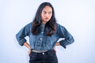 Elleri kalçasında bir kadın, kızgın ve hoşnutsuz bir ifade sergiliyor..