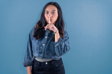 Endonezyalı, kot ceket giyen Asyalı kadın sessizlik işareti veriyor.